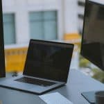 Laptop and monitor sitting in front of a window